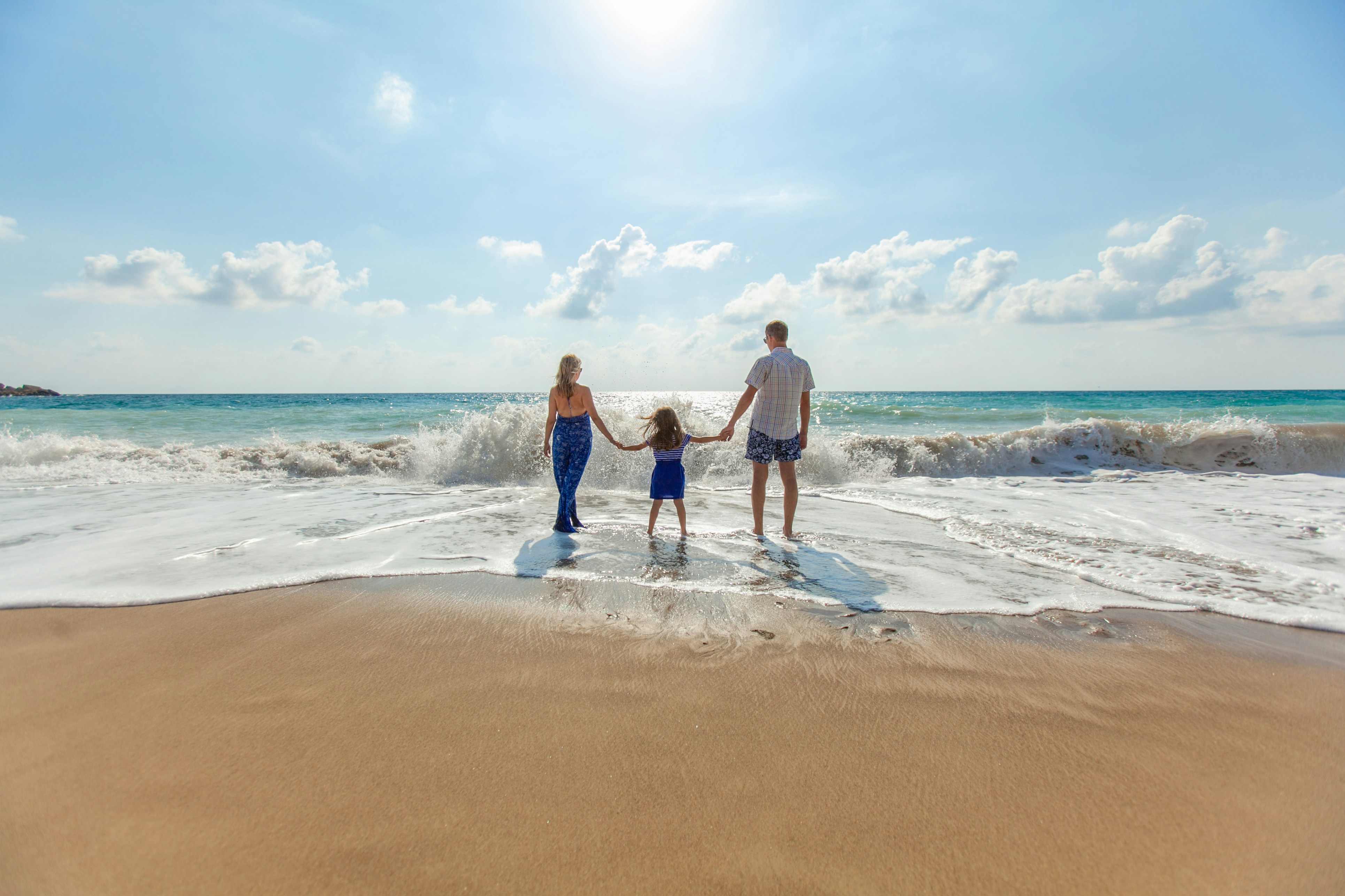 Familia caminando de la mano por la playa al atardecer